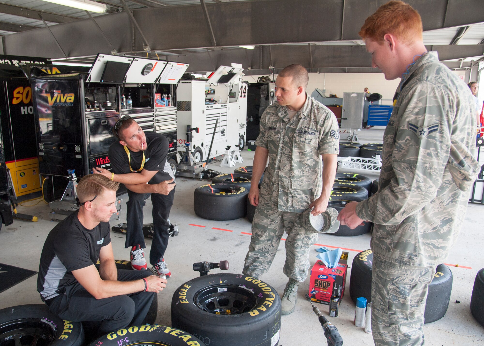 Chris Jackson, TriStar Motorsports mechanic, talks with Staff Sgt. Eliezer Ribeiro, 436th Logistics Readiness Squadron quality assurance inspector, and Airman 1st Class Elijah Baity, 436th LRS vehicle mechanic, about the differences between NASCAR and military vehicle tools and operations May 30, 2015, at Dover International Speedway in Dover, Del. Ribeiro and Baity were honorary pit crew members. (U.S. Air Force photo/Senior Airman Jared Duhon)