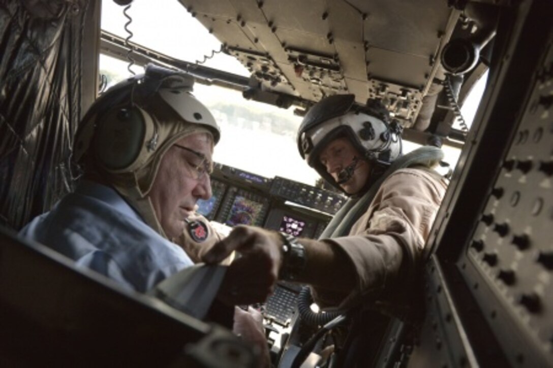 One of the pilots of an MV-22 Osprey tilt-rotor aircraft straps Defense Secretary Ash Carter into his seat before taking off to get a bird’s-eye view of the Strait of Malacca off the coast of Singapore, May 29, 2015. DoD Photo by Glenn Fawcett