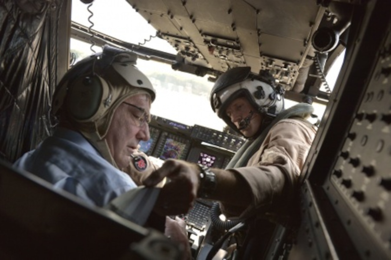 One of the pilots of an MV-22 Osprey tilt-rotor aircraft straps Defense Secretary Ash Carter into his seat before taking off to get a bird’s-eye view of the Strait of Malacca off the coast of Singapore, May 29, 2015. DoD Photo by Glenn Fawcett