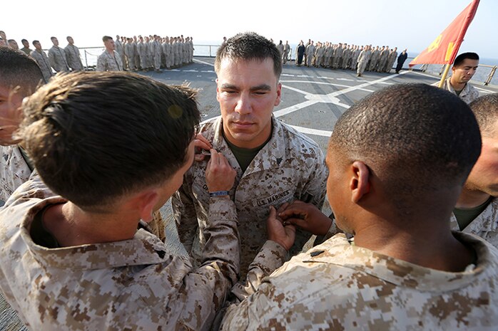 Corporal Fabaino E. Tornberg, left, a machine gunner, and Sgt. Rodrigue Maxius, right, a rifleman, pins corporal chevrons on Lance Cpl. Gregory Opinski, a machine gunner, all with Kilo Company, Battalion Landing Team 3rd Battalion, 6th Marine Regiment, 24th Marine Expeditionary Unit, during a promotion ceremony aboard the amphibious dock landing ship USS Fort McHenry (LSD 43), April 1, 2015. The 24th MEU is embarked on the ships of the Iwo Jima Amphibious Ready Group and deployed to maintain regional security in the U.S. 5th Fleet area of operations.  (U.S. Marine Corps photo by Sgt. Devin Nichols)