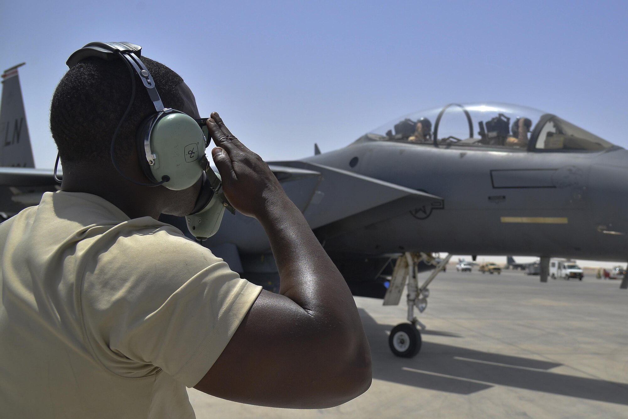 Staff Sgt. Oren renders a salute to F-15E Strike Eagle aircrew members as they taxi to the runway at an undisclosed location in Southwest Asia May 31, 2015. Sgt. Oren is a dedicated crew chief assigned to the 380th Expeditionary Aircraft Maintenance Squadron. (U.S. Air Force photo/Tech. Sgt. Christopher Boitz) 