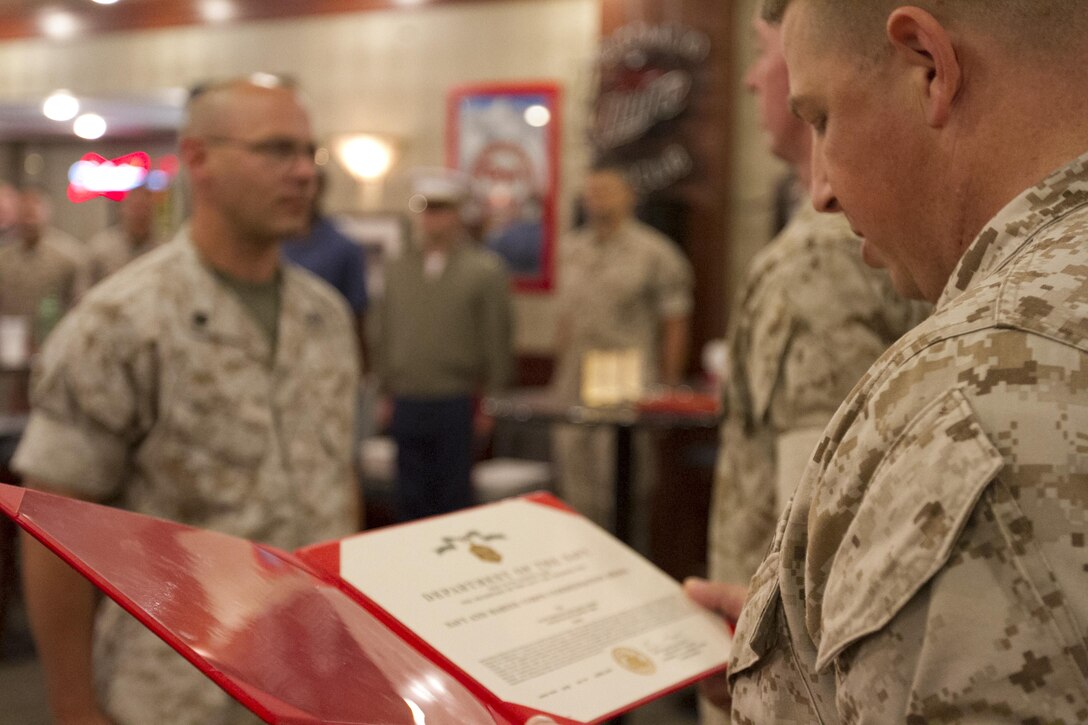 Master Sgt. Jason Bruce reads an end of tour award for Staff Sgt. Richard Miner during a Marine Corps Institute Company function at the Staff Non-Commissioned Officer club, Marine Barracks Washington, D.C., June 3, 2015.(U.S. Marine Corps photo by Cpl. Skye Davis/Released)