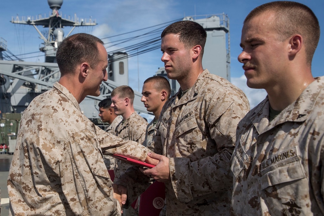 U.S. Marine Capt. Neil MacLaren, left, congratulates Cpl. Aaron Rose during a promotion ceremony aboard the USS Rushmore (LSD 47) at sea in the Pacific Ocean, June 1, 2015. MacLaren is the commanding officer for Kilo Company, Battalion Landing Team 3rd Battalion, 1st Marine Regiment, 15th Marine Expeditionary Unit. Rose is a rifleman with Kilo Co., BLT 3/1, 15th MEU. (U.S. Marine Corps photo by Sgt. Emmanuel Ramos/Released)