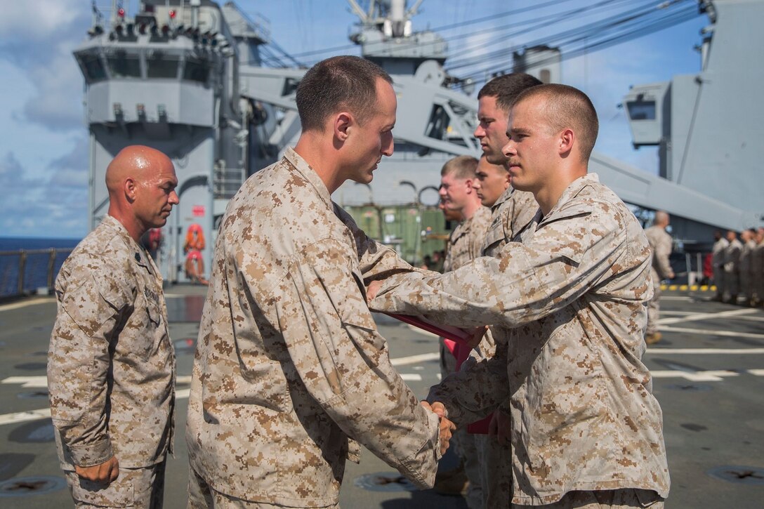 U.S. Marine Capt. Neil MacLaren, middle, congratulates Cpl. Hans Windahl during a promotion ceremony aboard the USS Rushmore (LSD 47) at sea in the Pacific Ocean, June 1, 2015. MacLaren is the commanding officer for Kilo Company, Battalion Landing Team 3rd Battalion, 1st Marine Regiment, 15th Marine Expeditionary Unit. Windahl is a squad leader with Kilo Co., BLT 3/1, 15th MEU. (U.S. Marine Corps photo by Sgt. Emmanuel Ramos/Released)
