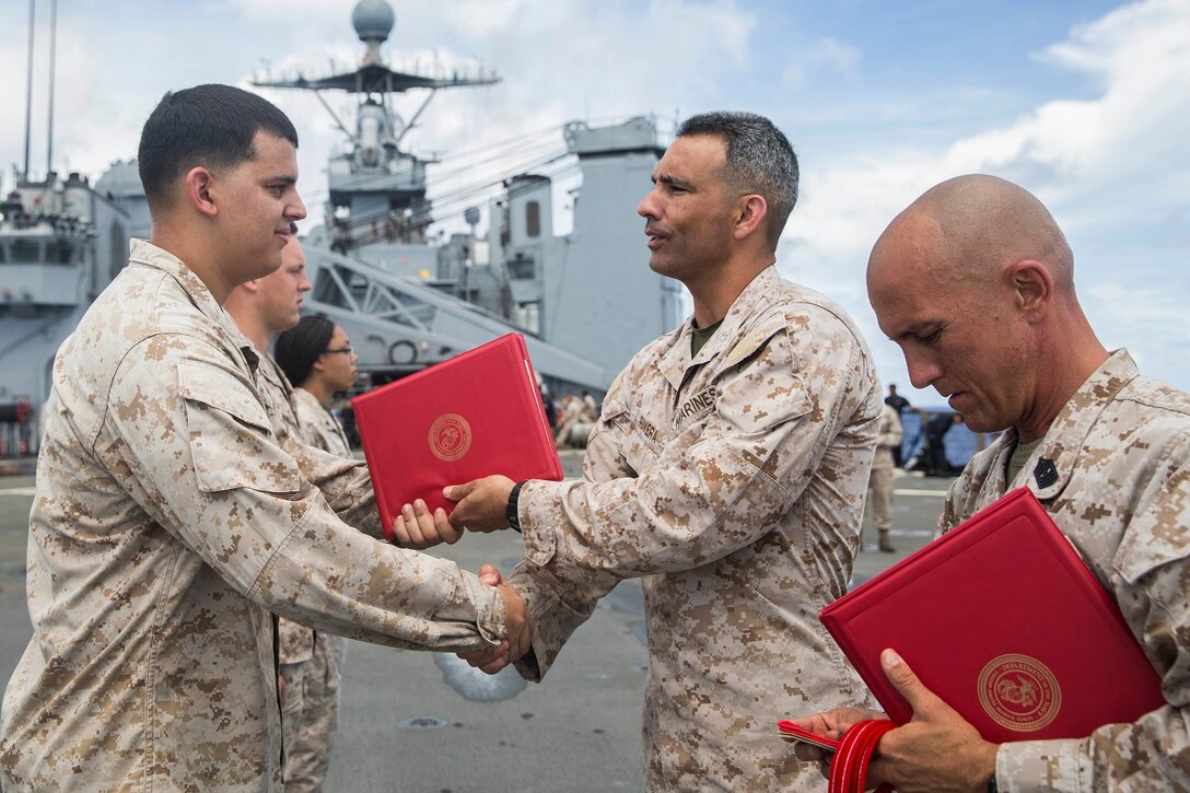 U.S. Marine Lt. Col. Wilfred Rivera, middle, congratulates Cpl. Dustin Ard during a promotion ceremony aboard the USS Rushmore (LSD 47) at sea in the Pacific Ocean, June 1, 2015. Rivera is the commanding officer of Combat Logistics Battalion 15, 15th Marine Expeditionary Unit. Ard is a landing support specialist with CLB-15, 15th MEU. (U.S. Marine Corps photo by Sgt. Emmanuel Ramos/Released)