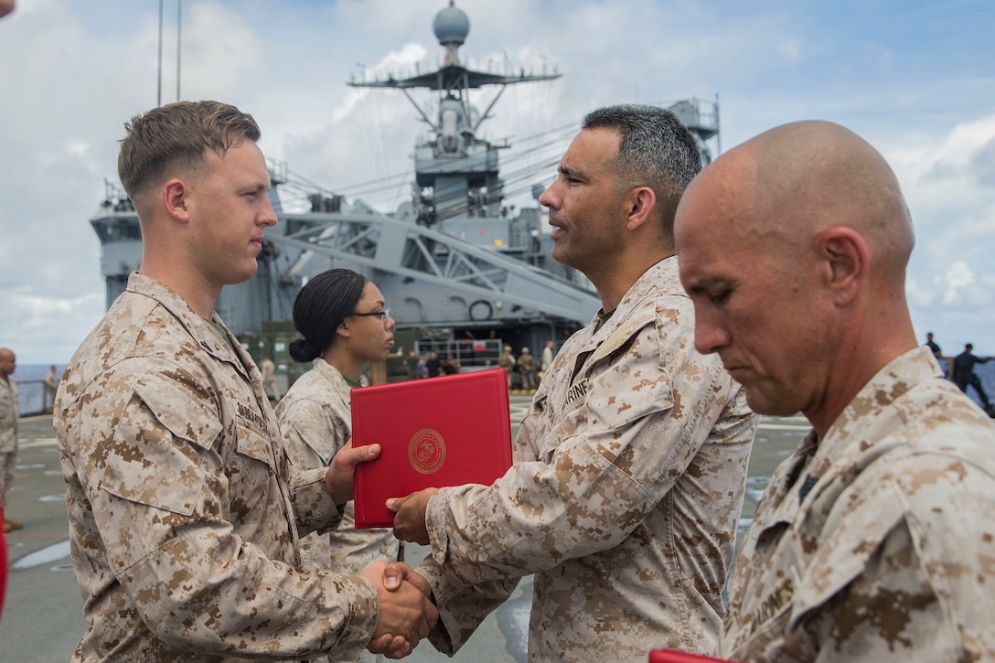 U.S. Marine Lt. Col. Wilfred Rivera, middle, congratulates Cpl. Martynas Dabravolskis during a promotion ceremony aboard the USS Rushmore (LSD 47) at sea in the Pacific Ocean, June 1, 2015. Rivera is the commanding officer of Combat Logistics Battalion 15, 15th Marine Expeditionary Unit. Dabravolskis is a landing support specialist with CLB-15, 15th MEU. (U.S. Marine Corps photo by Sgt. Emmanuel Ramos/Released)