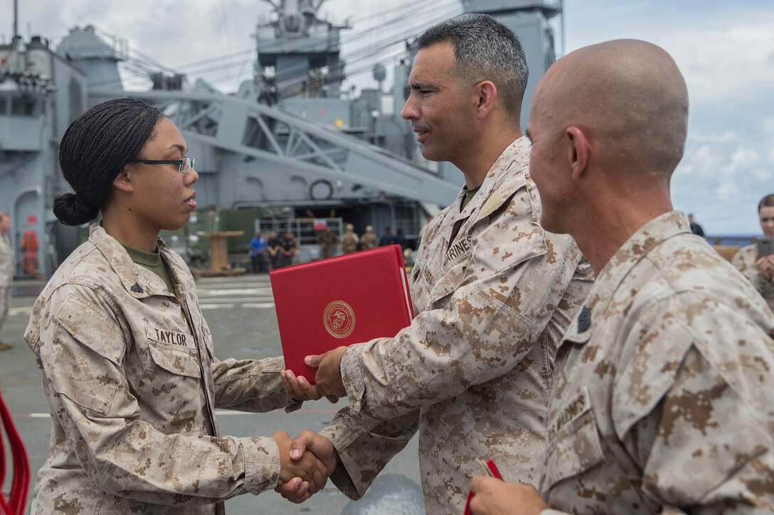 U.S. Marine Lt. Col. Wilfred Rivera, middle, congratulates Cpl. Tayleen Taylor during a promotion ceremony aboard the USS Rushmore (LSD 47) at sea in the Pacific Ocean, June 1, 2015. Rivera is the commanding officer of Combat Logistics Battalion 15, 15th Marine Expeditionary Unit. Taylor is a food service specialist with CLB-15, 15th MEU. (U.S. Marine Corps photo by Sgt. Emmanuel Ramos/Released)