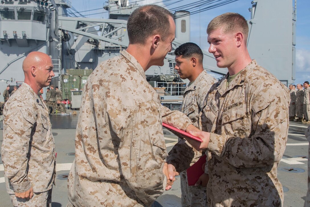 U.S. Marine Capt. Neil MacLaren, middle, congratulates Cpl. Alexander Delziel during a promotion ceremony aboard the USS Rushmore (LSD 47) at sea in the Pacific Ocean, June 1, 2015. MacLaren is the commanding officer for Kilo Company, Battalion Landing Team 3rd Battalion, 1st Marine Regiment, 15th Marine Expeditionary Unit. Delziel is a team leader with Kilo Co., BLT 3/1, 15th MEU. (U.S. Marine Corps photo by Sgt. Emmanuel Ramos/Released)