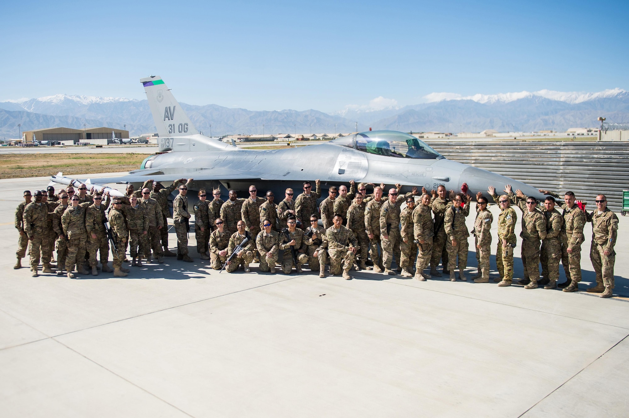 U.S. Air Force Brig. Gen. Mark D. Kelly, 455th Air Expeditionary Wing commander, Chief Master Sgt. Jeffery Brown, 455th AEW command chief, and Airmen assigned to the 455th AEW pose for a photo beside an F-16 fighting falcon aircraft as part of the “1000s of Hands” project at Bagram Air Field, Afghanistan, May 21, 2015. The project highlights the contributions of 455th AEW Airmen who bring decisive airpower to support NATO’s Resolute Support mission and Operation Freedom’s Sentinel. (U.S. Air Force photo by Tech. Sgt. Joseph Swafford/Released)