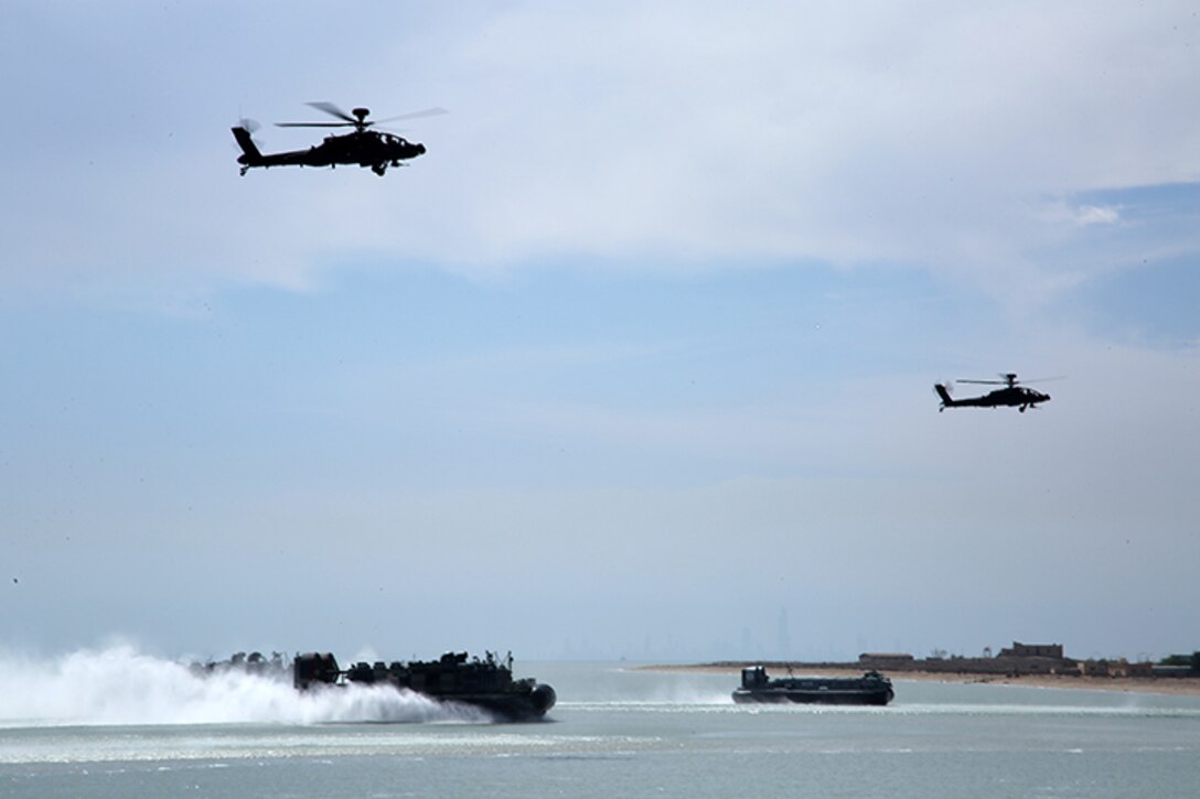 A U.S. Navy Landing Craft, Air Cushion vessel attached to the Iwo Jima Amphibious Ready Group and a Kuwaiti hovercraft approach the beach while being escorted by a pair of Kuwaiti Apache helicopters during an simulated amphibious assault as a part of Exercise Eagle Resolve 2015 at Failaka Island, Kuwait, March 24, 2015. Eagle Resolve is the premiere Arabian Peninsula/gulf region exercise among the United States, Gulf Cooperation Council nations, and international partners. It serves to address regional challenges associated with asymmetric/unconventional warfare in a multi-national environment. (U.S. Marine Corps photo by Sgt. Devin Nichols)