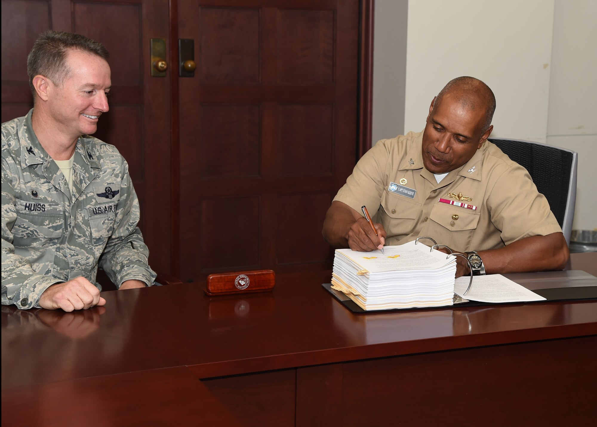 Col. Randall Huiss,15th Wing commander (left)and Navy Capt. Stanley Keeve Jr, Joint Base Pearl Harbor-Hickam commander, sign  the Joint Base Pearl Harbor-Hickam Integrated Defense Antiterrorism Plan on Joint Base Pearl Harbor-Hickam, Hawaii, June 4, 2015. The JBPHH IDAP provides requirement guidelines and procedures for implementing integrated defense and antiterrorism strategies. (U.S. Air Force photo by Tech. Sgt. Aaron Oelrich/Released)