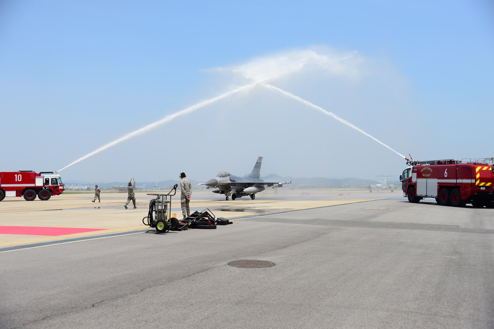 Taxiing in under overarching streams of pressurized water from fire trucks provided by the 51st Civil Engineer Fire Fighters, Col. Brook Leonard, 51st Fighter Wing commander, was greeted by family, friends, fellow commanders and other members of  Osan Air Base, Republic of Korea, June 4, 2015.
(USAF photo by Staff Sgt. Amber Grimm)