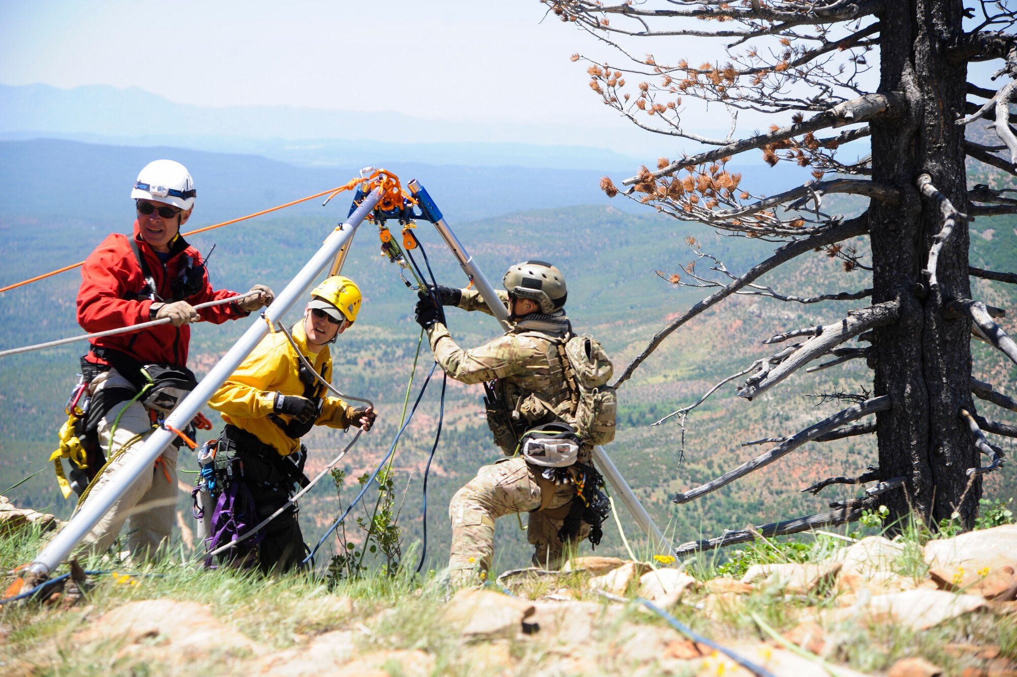Members of several interagency search and rescue teams and a 306th Rescue Squadron reserve pararescueman connect ropes to an Arizona Vortex Tripod during Angel Thunder 2015 high angle rescue training at Mongollon Rim, Ariz., June 3, 2015. Angel Thunder is the largest personnel recovery exercise in the world combining joint, coalition and interagency personnel. Participants will train through the full spectrum of personnel recovery capabilities with numerous types of aircraft. (U.S. Air Force photo by Senior Airman Betty R. Chevalier/Released)