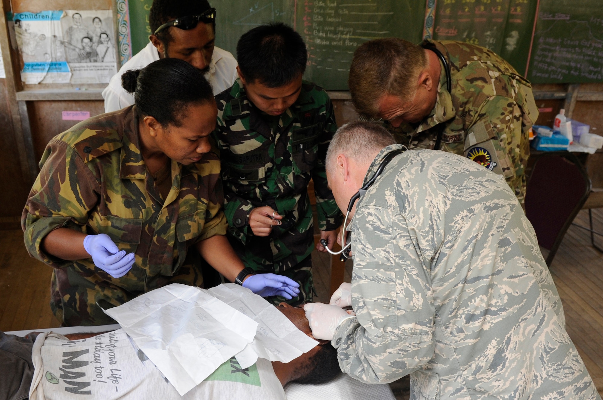 U.S. Air Force Lt. Col. Jeffrey Freeland, bottom right, Pacific Air Force chief of aerospace medicine from Joint Base Pearl Harbor-Hickam, Hawaii, removes a fatty tumor from a local man???s head while medical professionals from Papua New Guinea, Indonesia and the U.S. Air National Guard assist during Pacific Angel 15-4 at Unggai Primary School in Papua New Guinea, June 1, 2015. The medical team treated 514 patients by the end of their first day and reached a total of 2,000 patients treated in their three-day stay at their first health services outreach location. The mission of Pacific Angel is to upgrade education and health facilities in the area, as well as work to deepen local disaster response capabilities.  (U.S. Air Force photo by Staff Sgt. Marcus Morris/Released)