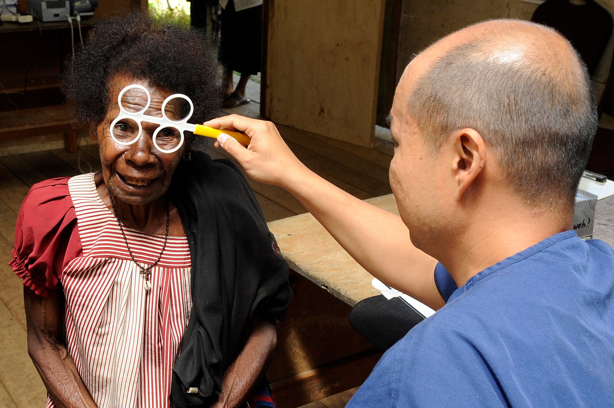 U.S. Air Force Lt. Col. Weilun Hsu, 374th Aerospace Medicine Squadron optometry flight commander from Yokota Air Base, Japan, determines which glasses to prescribe a local during Pacific Angel 15-4 at Unggai Primary School in Papua New Guinea, June 1, 2015. The optometrists prescribed more than 200 glasses, allowing the locals to walk away seeing better than before. (U.S. Air Force photo by Staff Sgt. Marcus Morris/Released)