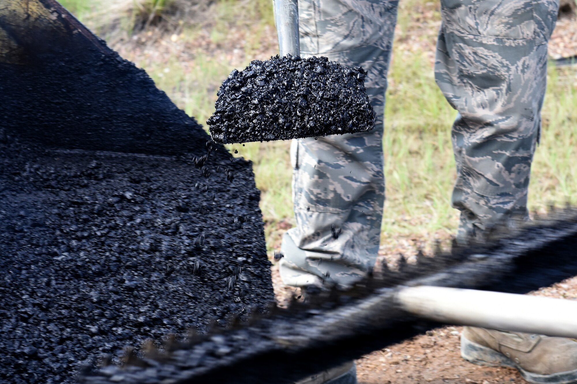 Members of the 341st Civil Engineer Squadron pavement and equipment section place hot-mix asphalt to repair defective pavement on Perimeter Road on Malmstrom Air Force Base, Mont., June 3, 2015. Road repair construction maintains 34.6 miles of road, 158.3 acres of paved parking lots, and 13.9 miles of sidewalks. (U.S. Air Force photo/Chris Willis)