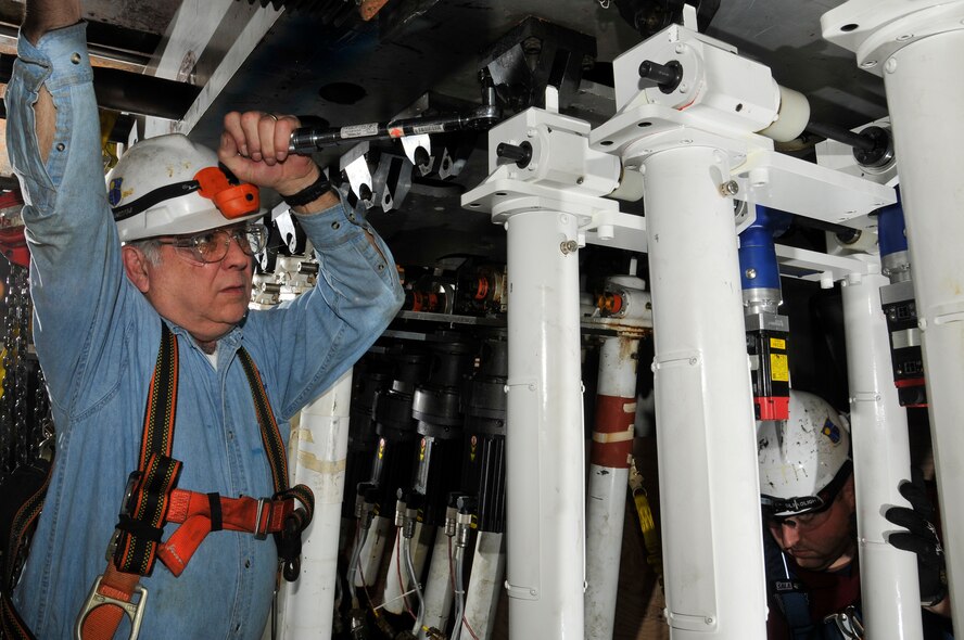 Dennis O’Dear (left) and Keith Gipson (bottom, right), both ATA outside machinists, install newly designed and fabricated flexible nozzle actuators in the Propulsion Wind Tunnel four-foot transonic wind tunnel (4T) at AEDC. The actuators are electromechanically driven ball-screw jacks which move the flexible top and bottom plates in the 4T tunnel closer together providing variable Mach numbers or wind speeds during a test. (Photo by Rick Goodfriend)