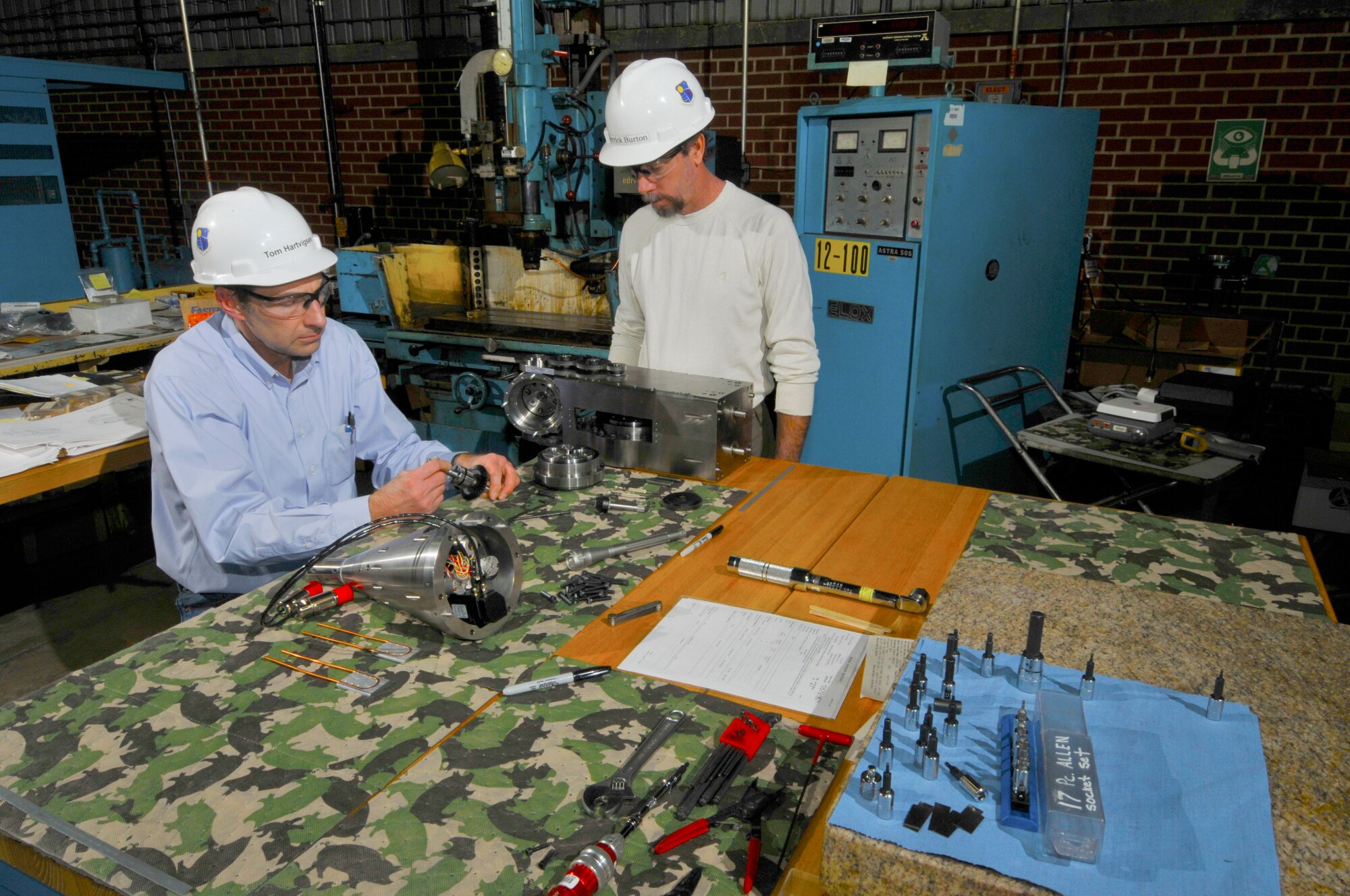 Tom Hartvigsen (left), a test system designer with the ATA Technology and Engineering Analysis Branch, and Derrick Burton, a Model Shop machinist with the ATA Test Support Branch, assemble parts that were fabricated by the shop for the new pitch boom mechanism for the Propulsion Wind Tunnel four-foot transonic wind tunnel (4T) Captive Trajectory Support (CTS) System. The pitch boom mechanism controls the pitch, yaw and roll movement of a bomb or missile when it separates from the aircraft during a flight simulation test at altitude conditions. (Photo by Rick Goodfriend)