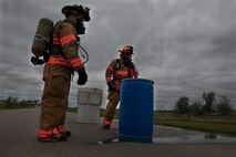 Members of the 5th Civil Engineer Squadron prepare to place a barrel leaking simulated hazardous material into another barrel to prevent any further harm during an exercise at Minot Air Force Base, N.D., May 29, 2015. The exercise tested the timeliness and efficiency of first responders in a hazardous material situation. (U.S. Air Force photo/Airman 1st Class Christian Sullivan)