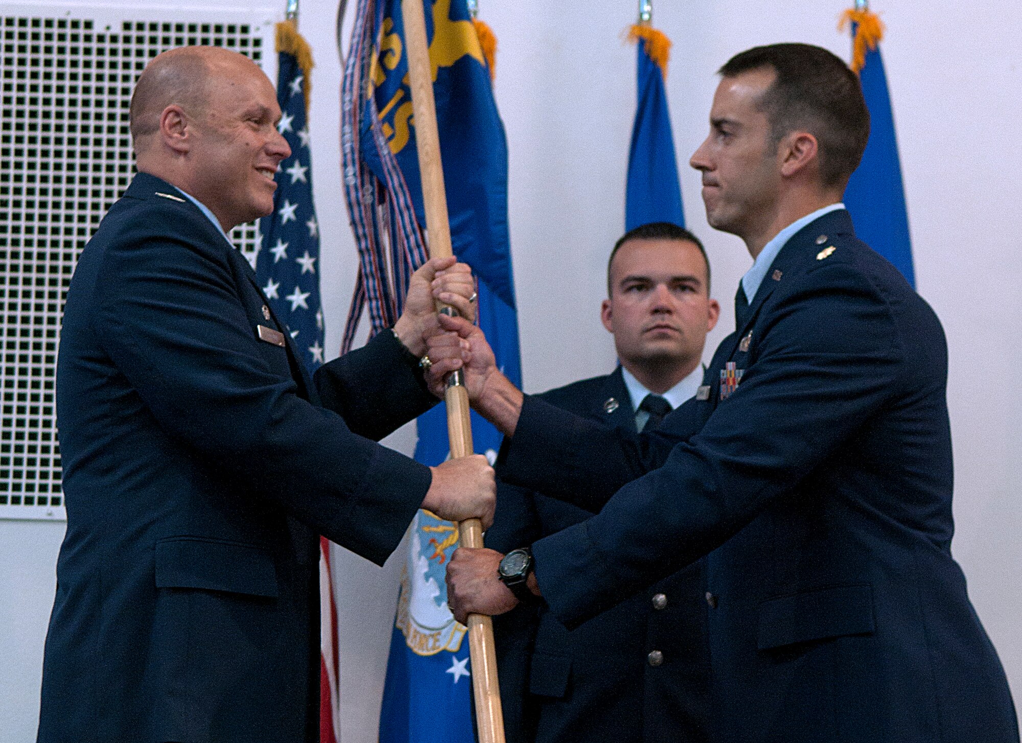 Col. Travis Condon, 90th Mission Support Group commander, passes the guidon to Maj. James Simmons, 90th Contracting Squadron commander, during the 90th CONS change of command ceremony June 3, 2015, at F.E. Warren Air Force Base. The ceremony signified the transition of command from Maj. Katrina Curtis to Simmons. Master Sgt. Ian Lutjens, 90th CONS base acquisition flight NCO in-charge , stands-by to take the guidon from Simmons. (U.S. Air Force photo by Airman 1st Class Brandon Valle)