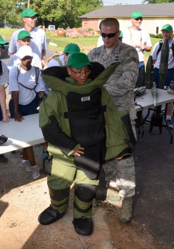 Air National Guard Senior Airman Kyle Campbell, a 116th Civil Engineering Squadron explosive ordnance disposal technician, helps an Air Force Junior ROTC student try on a bomb suit to experience the weight of the protective outerwear at Camp John Hope in Fort Valley, Ga., June 3, 2015.  The demonstration was part of the Houston County Joint AFJROTC Cadet Summer Leadership Program that provided more than 100 cadets from five local high schools an overview of various Air Force career fields. (Air National Guard photo by Tech. Sgt. Julie Parker/Released)