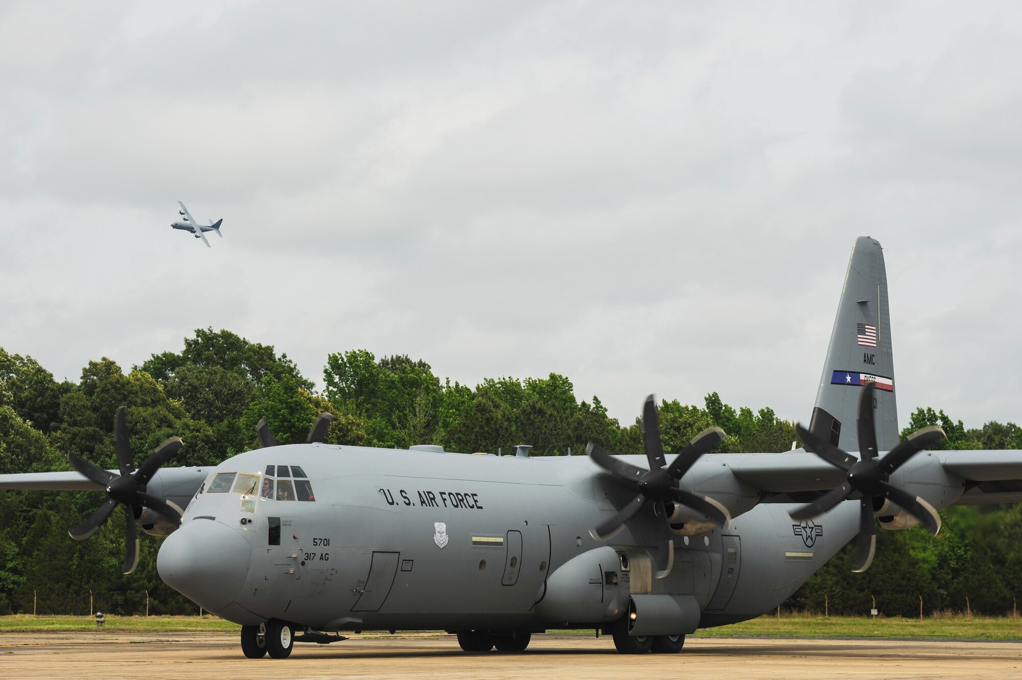 A C-130J prepares to land as another C-130J on the ground prepares for departure May 20, 2015, at Little Rock Air Force Base, Ark. The C-130 is one of the most versatile cargo delivery aircraft in the U.S. Air Force for its airdrop and air-land mission capabilities (U.S. Air Force photo by Senior Airman Harry Brexel)