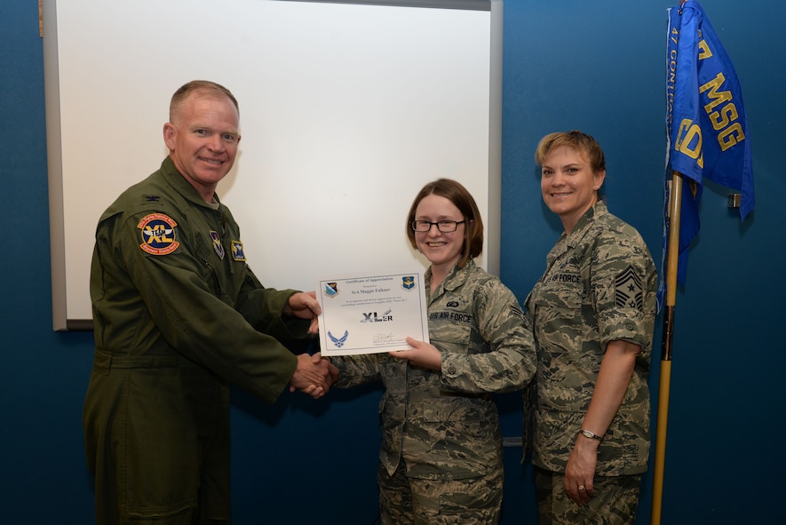 Senior Airman Maggie Falkner, center, 47th Contracting Flight contracting officer, poses with Col. Darrell Judy, 47th Flying Training Wing vice commander, and Chief Master Sgt. Teresa Clapper, 47th FTW command chief, after accepting the XLer of the Week award here May 25, 2015. The XLer is a weekly award chosen by wing leadership and is presented to those who consistently make outstanding contributions to their unit and Laughlin. (U.S. Air Force photo by Airman Brandon May)