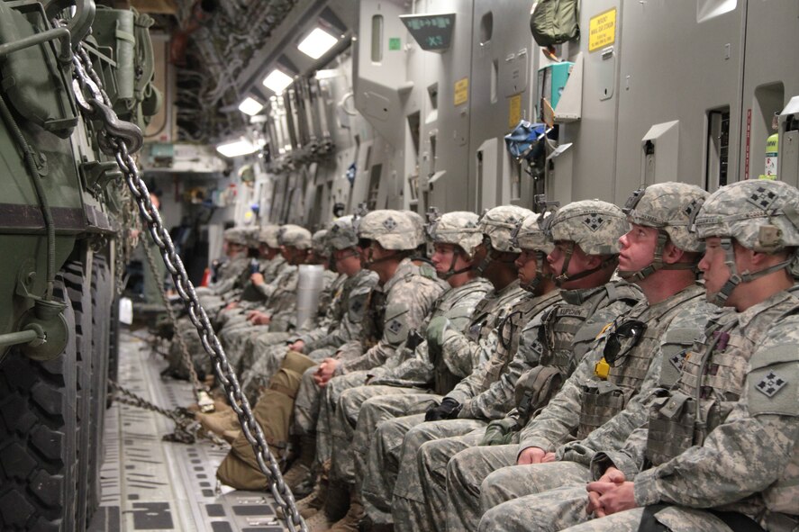 Soldiers of 2nd Battalion, 23rd Infantry Regiment, 1st Stryker Brigade Combat Team, 4th Infantry Division, prepare for their flight on a C-17 Globemaster III to the National Training Center in Fort Irwin, Calif., with their Strykers chained down in front of them, May 21, 2015.