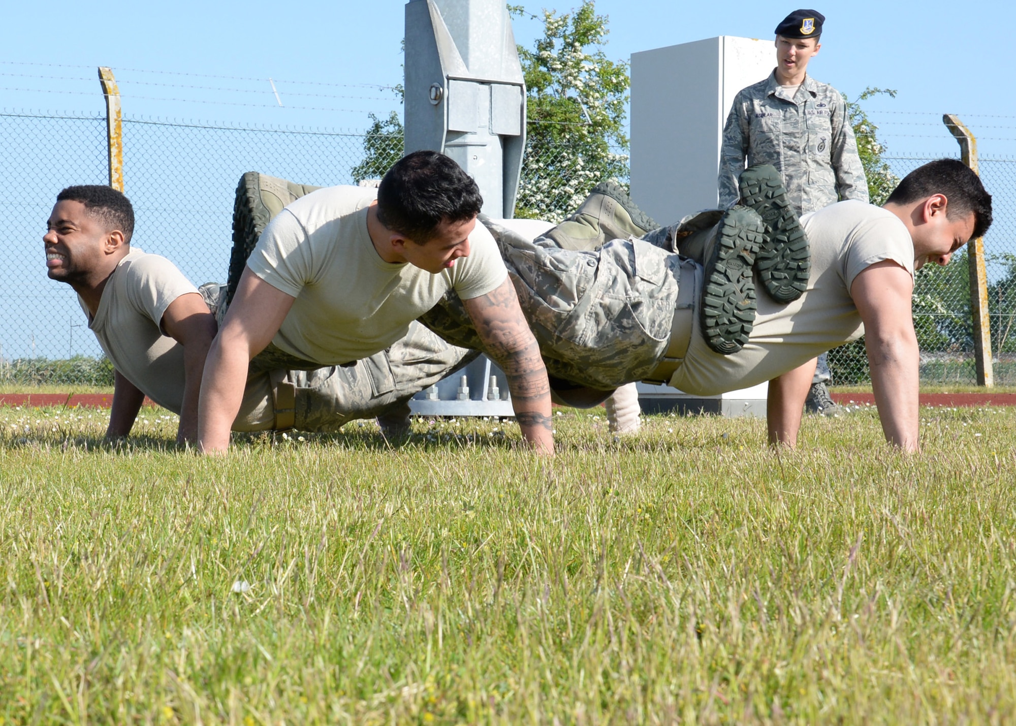 Members from the 100th Security Forces Squadron and the 48th Security Forces Squadron take part in the “Team Pain” portion of a “Defender Challenge” May 21, 2015, on RAF Mildenhall, England. "Team Pain" consisted of each member placing their feet and legs on team members’ backs and performing as many pushups as they could in one minute. (U.S. Air Force photo by Gina Randall/Released)