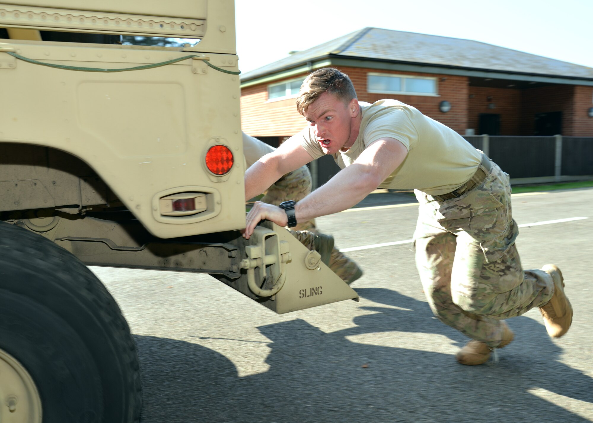 U.S. Air Force Senior Airman Evan Angelesey, 48th Security Forces Squadron criminal investigator from Kennewick, Wash., pushes a Humvee with his teammates, during the “Defender Challenge” event May 21, 2015, on RAF Mildenhall, England. The joint security forces challenge with RAF Mildenhall and RAF Lakenheath defenders was held as part of National Police Week and included a tire flip, M-4 rifle and M-9 pistol disassemble and reassemble, a team push-ups event, low and high-crawl and self-aid buddy care. (U.S. Air Force photo by Karen Abeyasekere/Released)