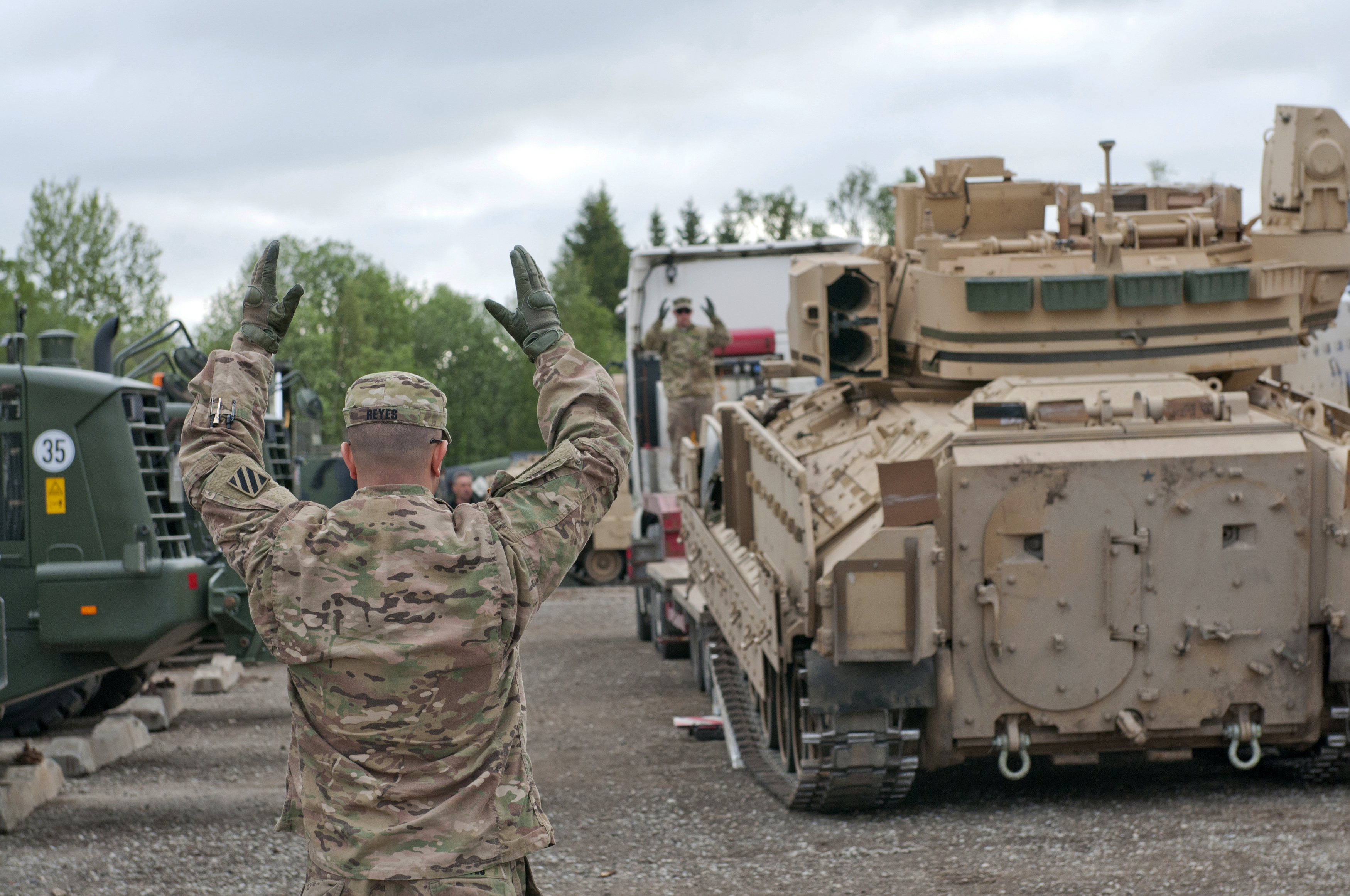 U.S. Army Sgt. Yasmani Reyes helps direct an M2A3 Bradley Fighting Vehicle off a flatbed during