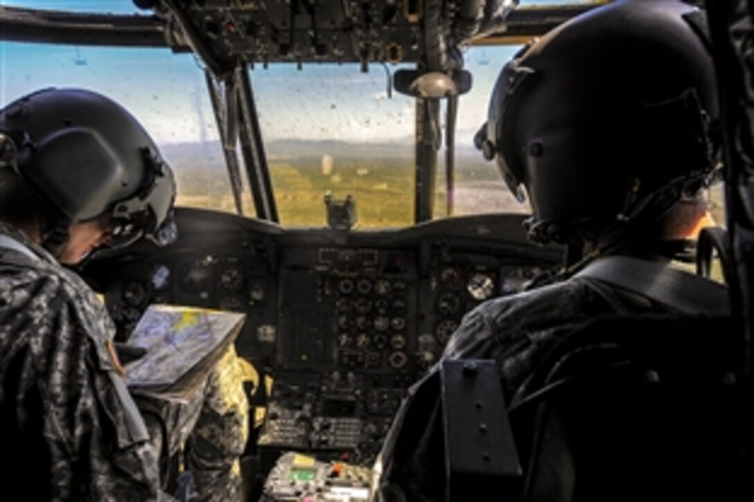 Army Capt. Drew Rowland, right, steers a CH-47D as 1st Lt. Erik Poser reads a sectional aeronautical chart during Angel Thunder while flying over southern Arizona, June 2, 2015. Angel Thunder is the largest joint service, multinational, interagency combat search and rescue exercise. Rowland and Poser are pilots assigned to Task Force Tatanka.