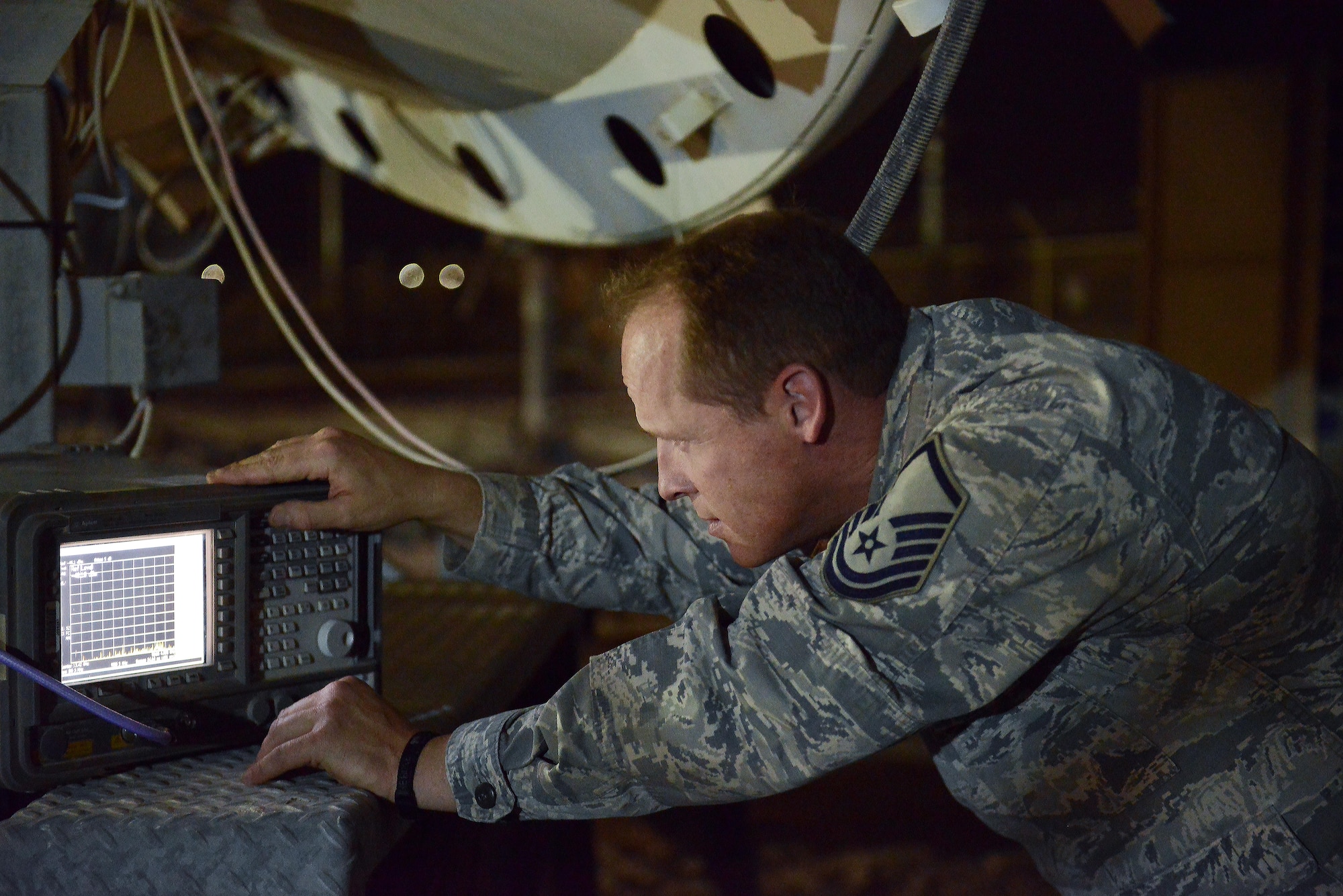 Master Sgt. Brian Popham, 379th Expeditionary Operations Support Squadron Silent Sentry, monitors and adjusts signal strength from an antenna during routine maintenance checks signal May 27, 2015 at Al Udeid Air Base, Qatar. The Silent Sentry team monitors high priority satellite communication signals, detects electromagnetic interference on those signals and geolocates the source of that interference along with other signals of interest. (U.S. Air Force photo/Staff Sgt. Alexandre Montes)