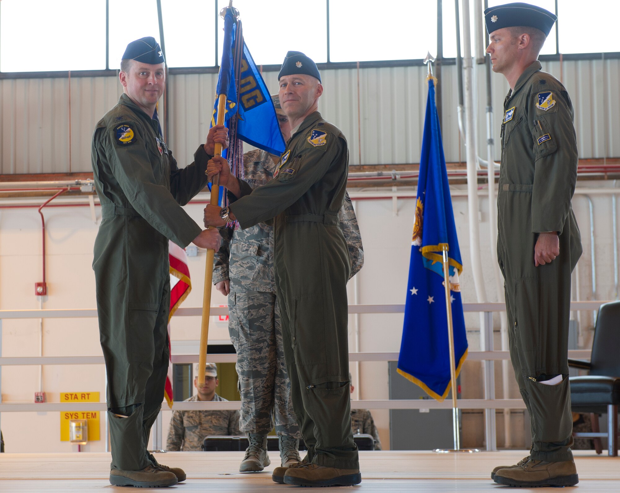 LLt. Col. Calvin Powell, outgoing commander, passes the 16th Training Squadron guidon to Col. Robert Kiebler, 49th Wing commander, symbolizing a seamless change of command at Holloman Air Force Base, N.M., June 5. In the ceremony Lt. Col Adam Palmer assumed command of the 16th TRS from Powell. The 16th TRS is the United States Air Force’s only training squadron responsible for providing administrative and instructional support to MQ-1B Predator and MQ-9 Reaper Formal Training Units (U.S. Air Force photo by Staff Sgt. Stacy Moless/Released)