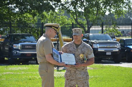 Commander J. Michael Cole presents Lance Cpl. Victor Padilla with a certificate after being awarded the Navy and Marine Corps Commendation Medal April 21, 2015 at the Naval Consolidated Brig Charleston on Joint Base Charleston, S.C. Padilla was awarded the medal for saving his best friend and fellow marine from a suicide attempt on April 11, 2015. The Navy and Marine Corps Commendation Medal is reserved for Sailors and Marines who distinguish themselves through heroic or meritorious achievement. Cole is the commanding officer of the NCBC and Padilla is a correction specialist at NCBC. (Courtesy photo / Naval Consolidated Brig Charleston) 
