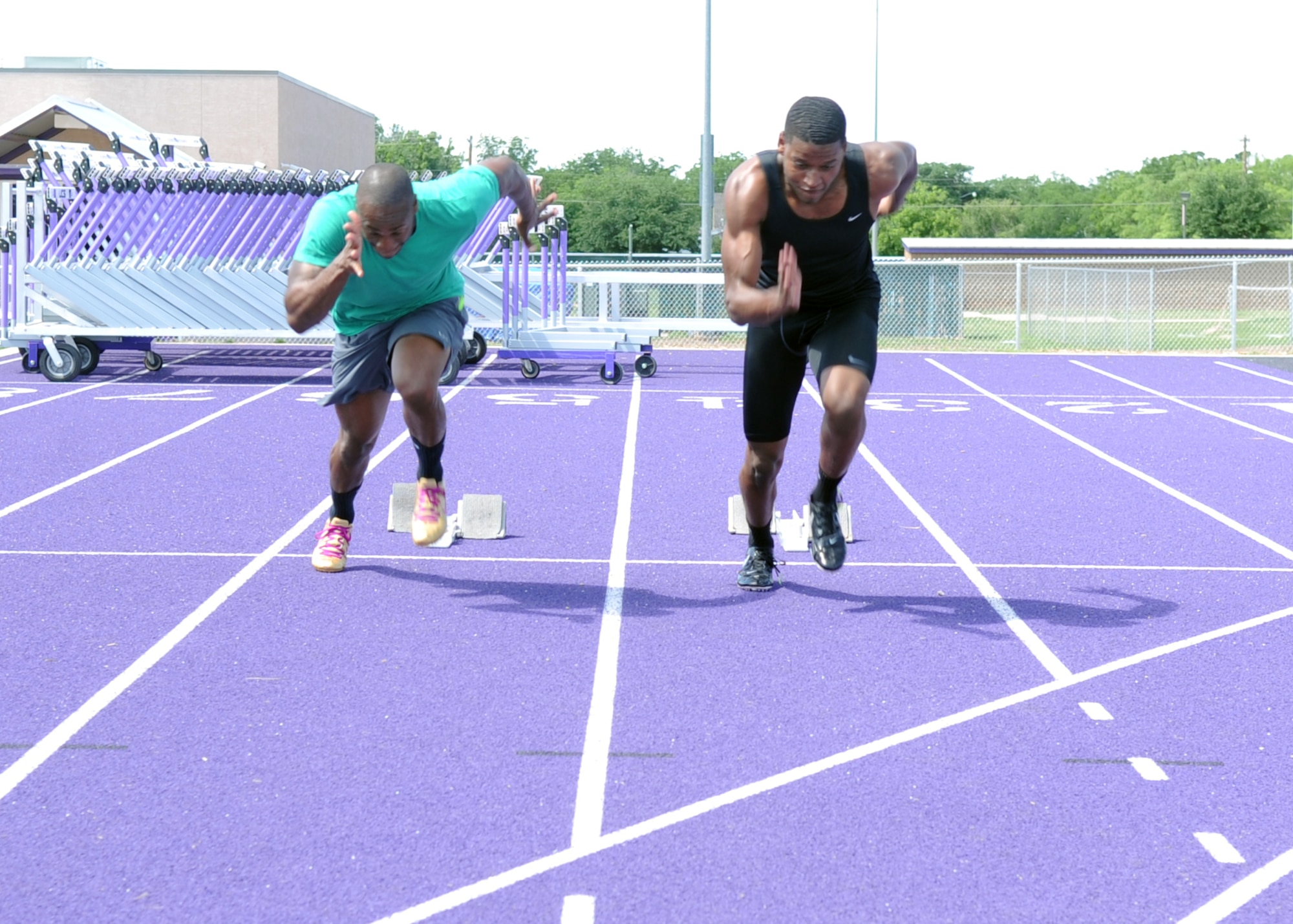 U.S. Air Force Senior Airmen Kwesi Toney, left, 7th Logistics Readiness Squadron equipment accountability clerk, and Parnelle Shands, 317th Aircraft Maintenance Squadron crew chief, practice coming out of starting blocks together at Abilene Christian University May 18, 2015, in Abilene, Texas. Both Airmen attended a training camp at Ramstein Air Base, Germany, for the U.S. Air Forces in Europe track and field team. (U.S. Air Force photo by Senior Airman Shannon Hall/Released)