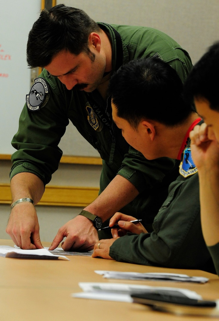 Capt. Walt Coombs, 35th Fighter Squadron pilot, briefs Republic of Korea Air Force pilots from the 123rd Tactical Fighter Squadron, Seosan Air Base, at Kunsan Air Base, ROK, during Exercise Buddy Wing 15-4, June 4, 2015. In an effort to enhance U.S. and ROKAF combat capability, Buddy Wing exercises are conducted multiple times throughout the year on the peninsula to sharpen interoperability between the allied forces so that if need be, they are always ready to fight as a combined force. (U.S. Air Force photo by Staff Sgt. Nick Wilson/Released)
