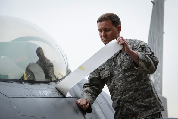 Staff Sgt. Justin Wilson, 35th Aircraft Maintenance Squadron dedicated F-16 Falcon crew chief, unveils the name of the incoming United States Forces, Japan, and 5th Air Force commander, on an F-16 at Yokota Air Base, Japan, June 5, 2015. Lt. Gen. John Dolan assumed command from Lt. Gen. Salvatore Angelella during the change of command ceremony. Wilson is stationed at Kadena Air Base, Japan. (U.S. Air Force photo by Staff Sgt. Cody H. Ramirez/Released)

