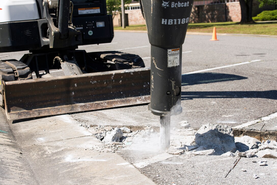 An Airman from the 23d Civil Engineer Squadron operates a mini excavator with a jackhammer attachment June 1, 2015, at Moody Air Force Base, Ga. The 23d CES heavy equipment operators conducted a two-day project to repair concrete sinking on Gardner St. (U.S. Air Force photo by Airman Greg Nash/Released)