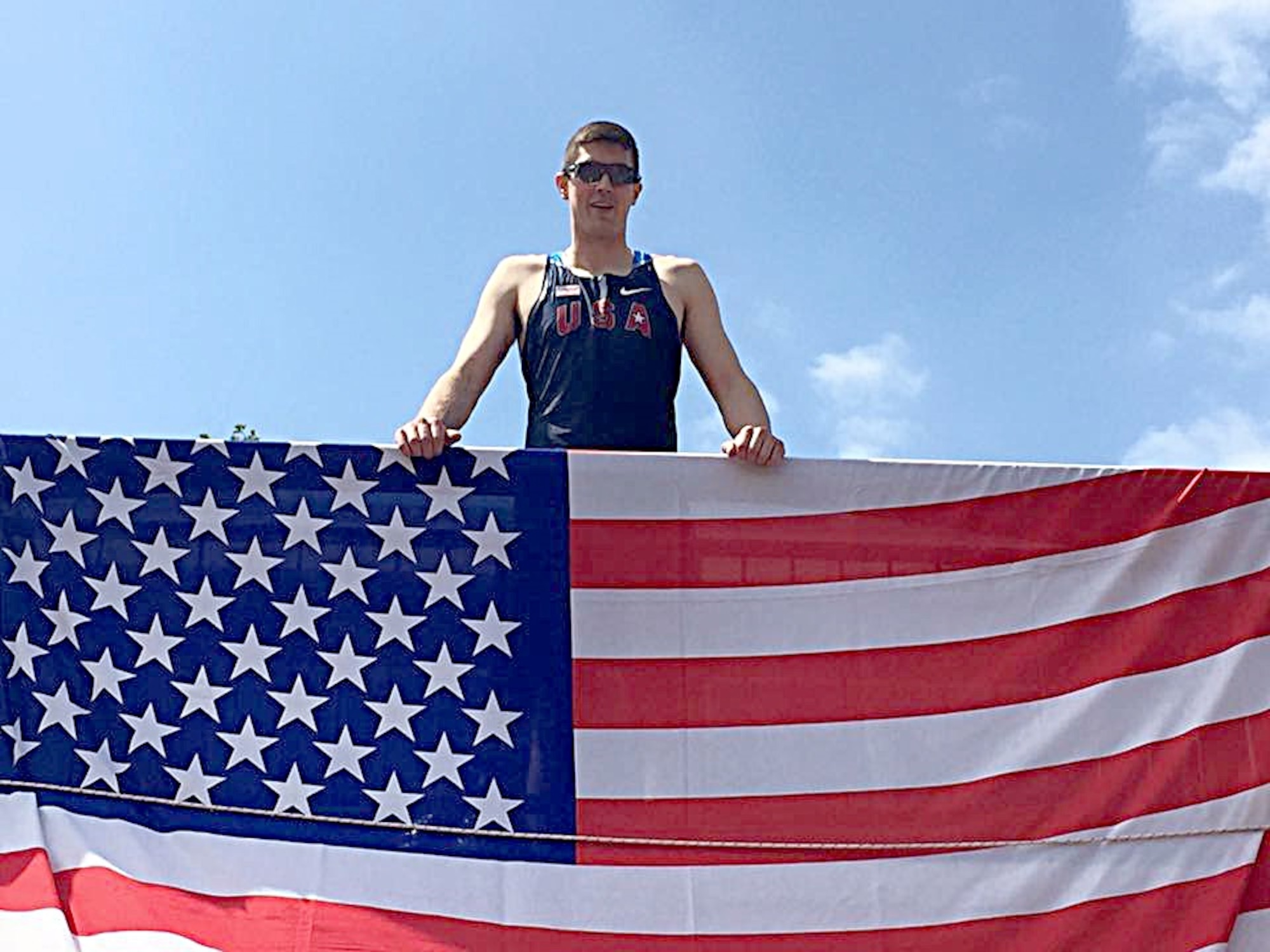 First Lt. Zachariah Wood, 509th Comptroller Squadron budget analyst at Whiteman Air Force Base, Mo., poses behind the American flag in Amsterdam during the Headquarters Allied Air Component Command Track and Field Championship held recently. Wood, along with his long-time friend, 2nd Lt. Rachel Herald, 90th Logistics Readiness Squadron installation deployment officer at F.E. Warren Air Force Base, Wyo., took first place in the high jump for the men’s and women’s categories respectively. (Courtesy photo)