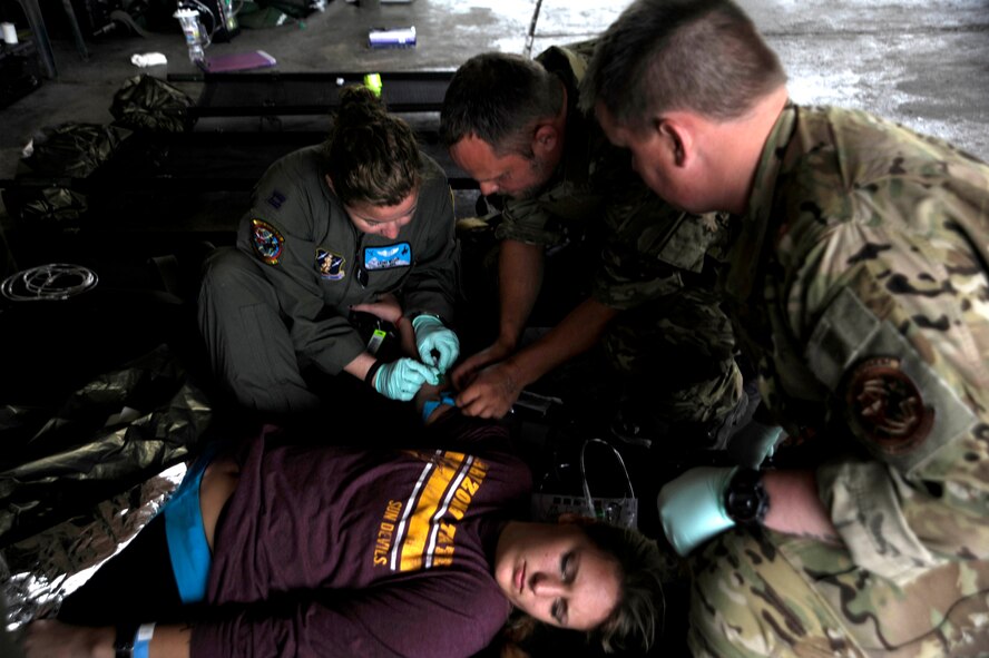 U.S. Air Force Airmen and a Royal Danish Air Force rescue member treat a simulated flood victim with internal bleeding during an Angel Thunder 2015 mass casualty exercise at Winslow???Lindbergh Regional Airport, Ariz., June 5, 2015. Service members, University of Arizona and Northern Arizona University students acted as simulated patients to create a realistic experience during the exercise. (U.S. Air Force photo/Tech. Sgt. Courtney Richardson/Released)  

