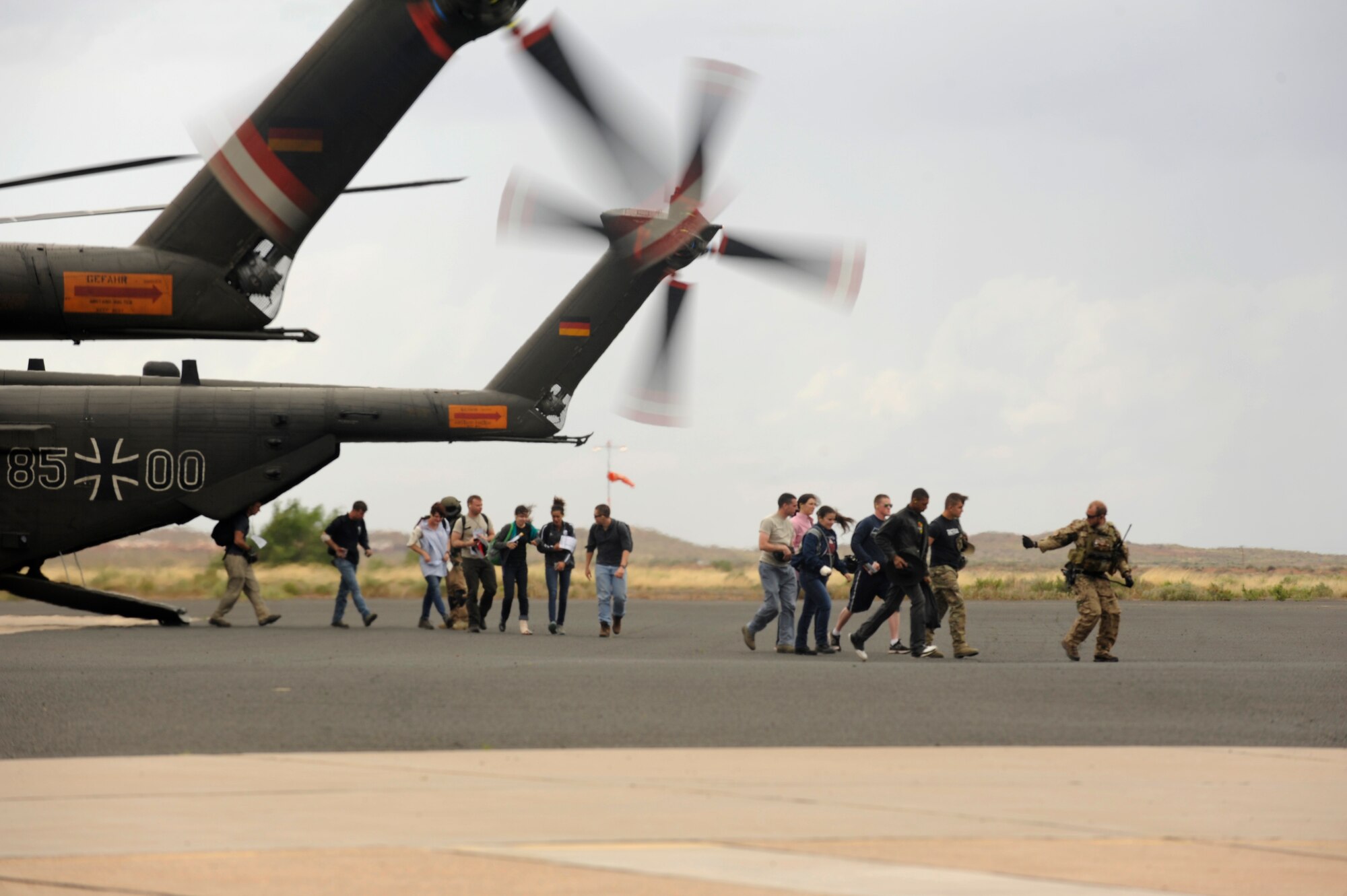 Simulated flood victims are escorted from a German Air Force CH-53GS helicopter a German Air Force pararescueman during an Angel Thunder 2015 mass casualty exercise at Winslow-Lindbergh Regional Airport, Ariz., June 5, 2015. U.S. military forces and partner- nations worked together during the exercise to transport simulated patients from Camp Navajo Training Site to the casualty collection point located at the Winslow-Lindbergh Regional Airport. (U.S. Air Force photo/Tech. Sgt. Courtney Richardson/Released)
