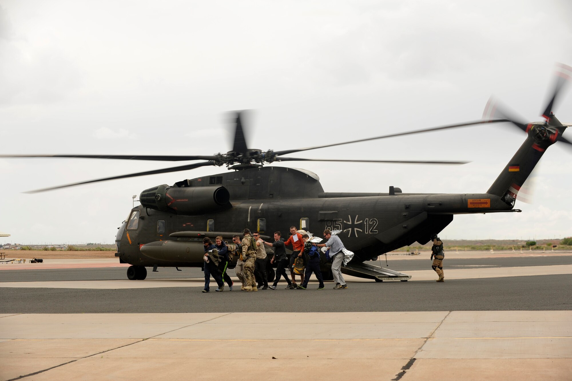 Simulated flood victims are escorted from a German Air Force Air Force CH-53GS helicopter during an Angel Thunder 2015 mass casualty exercise at Winslow-Lindbergh Regional Airport, Ariz., June 5, 2015. U.S. military forces and partner-nations worked together during the exercise to transport simulated patients from Camp Navajo Training Site to the casualty collection point located at the Winslow-Lindbergh Regional Airport. (U.S. Air Force photo/Tech. Sgt. Courtney Richardson/Released)