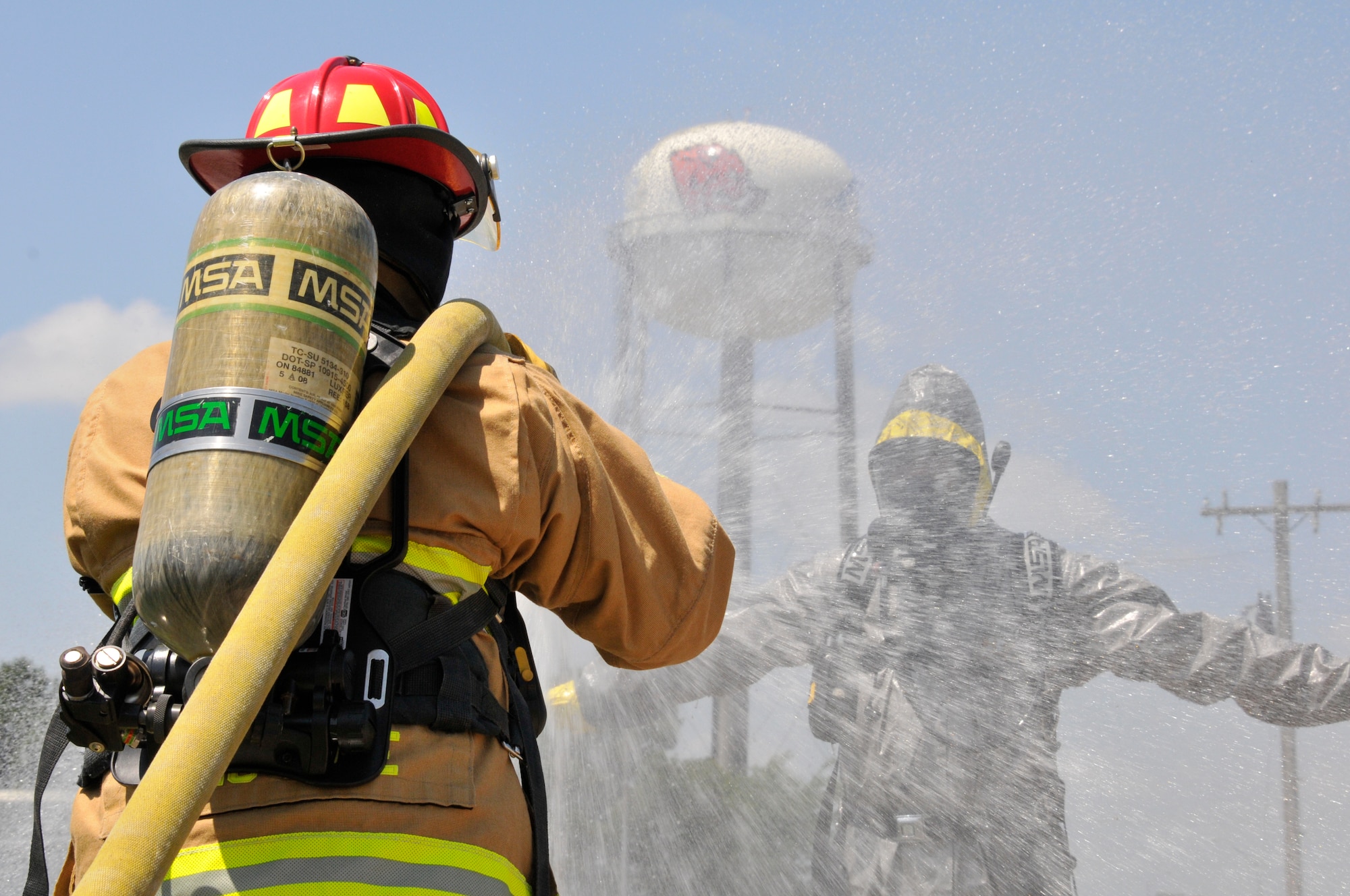 Staff Sgt. Kyle Moore, 188th Fire Emergency Services Flight firefighter, sprays Senior Airman William Fine, 188th Emergency Management journeyman, with water to simulate the decontamination process of a hazardous materials response. Firefighters and emergency management personnel are trained to respond to HAZMAT incidents or other emergency situations on base. (U.S. Air National Guard photo by Staff Sgt. John Suleski/Released)