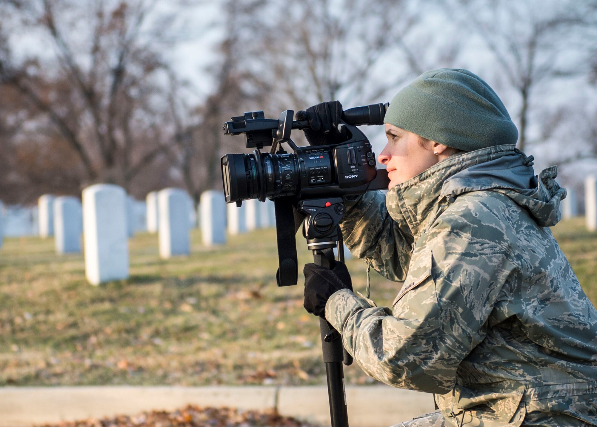 Staff Sgt. Nikoletta Kanakis, a Massachusetts Air National Guard broadcaster deployed to Air Force Mortuary Affairs Operations at Dover Air Force Base, Del., captures video footage during a wreath laying event at Arlington National Cemetery, Dec. 13, 2014. Kanakis' primary duty is to document the dignified transfer of human remains to be provided to families of the fallen. (U.S. Air Force photo by Captain Raymond Geoffroy/Released)