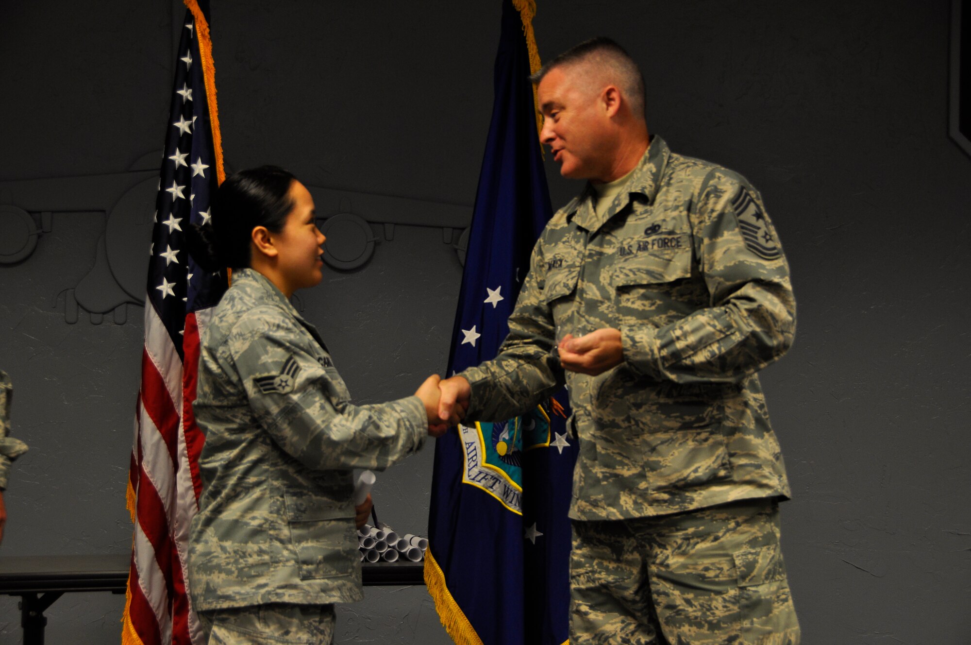 Senior Airman Anna Azcarraga, 446th Maintenance Squadron, shakes hands with Chief Master Sgt. Anthony Mack, 446th Airlift Wing command chief, after receiving her CCAF diploma. The original ceremony only allowed five of nearly 60 graduates to walk because of its difficult time and location. In order to allow Reservists to walk at their own graduation, Col. Scott McLaughlin, 446th Airlift Wing commander, and Mack hosted their own graduation ceremony at the 446th Airlift Headquarters auditorium. (Air Force Reserve photo by Senior Airman Madelyn McCullough)