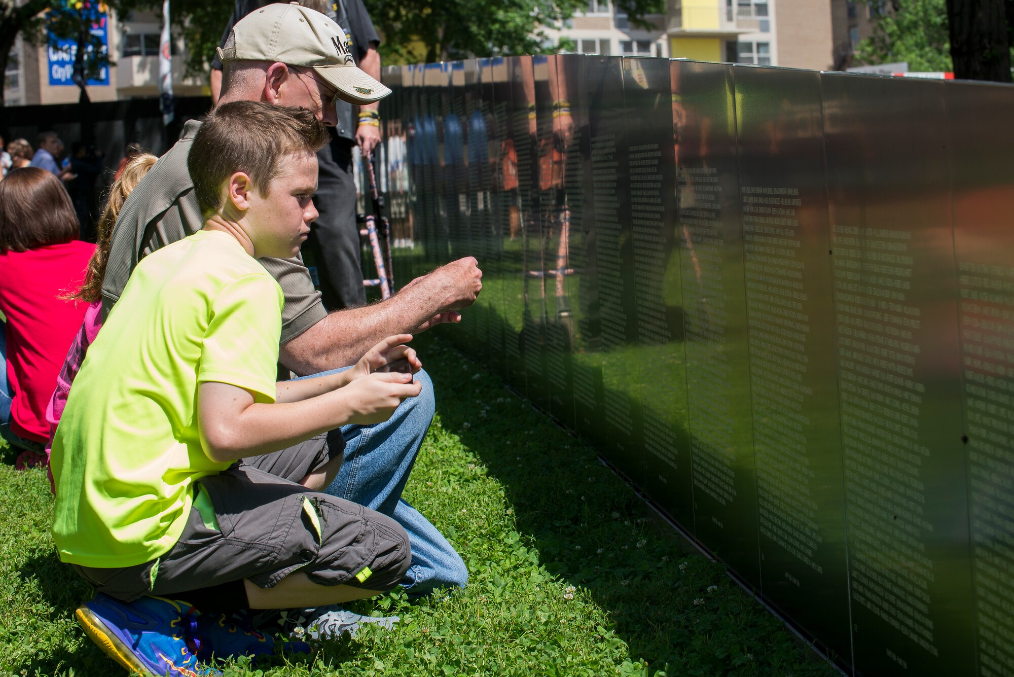 A family looks at the name of a family member they lost in the Vietnam War at the Eternal Flame Park, St. Louis, Missouri, June 5, 2015. The Traveling Vietnam Wall is a tribute dedicated to the memory of the servicemembers who lost their lives in the Vietnam War. (U.S. Air Force Photo by Airman 1st Class Megan Friedl)