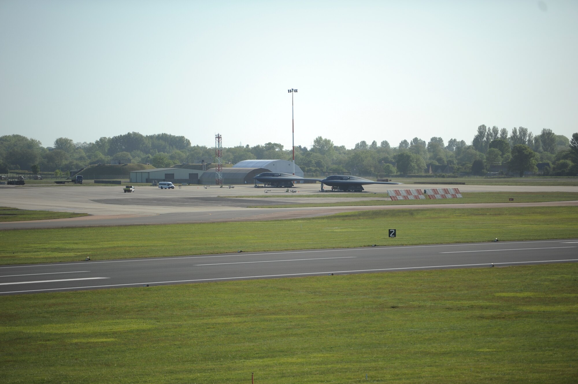 Two B-2 Spirits await refueling on the flightline at Royal Air Force Fairford, England, June 7, 2015 as a hot-pit refueling and an engine-running crew change occur. The two skills were tested at RAF Fairford highlighting the ability of the aircraft to forward deploy and deliver conventional and nuclear deterrence anytime and anywhere. (U.S. Air Force photo/Capt. Christopher Mesnard)