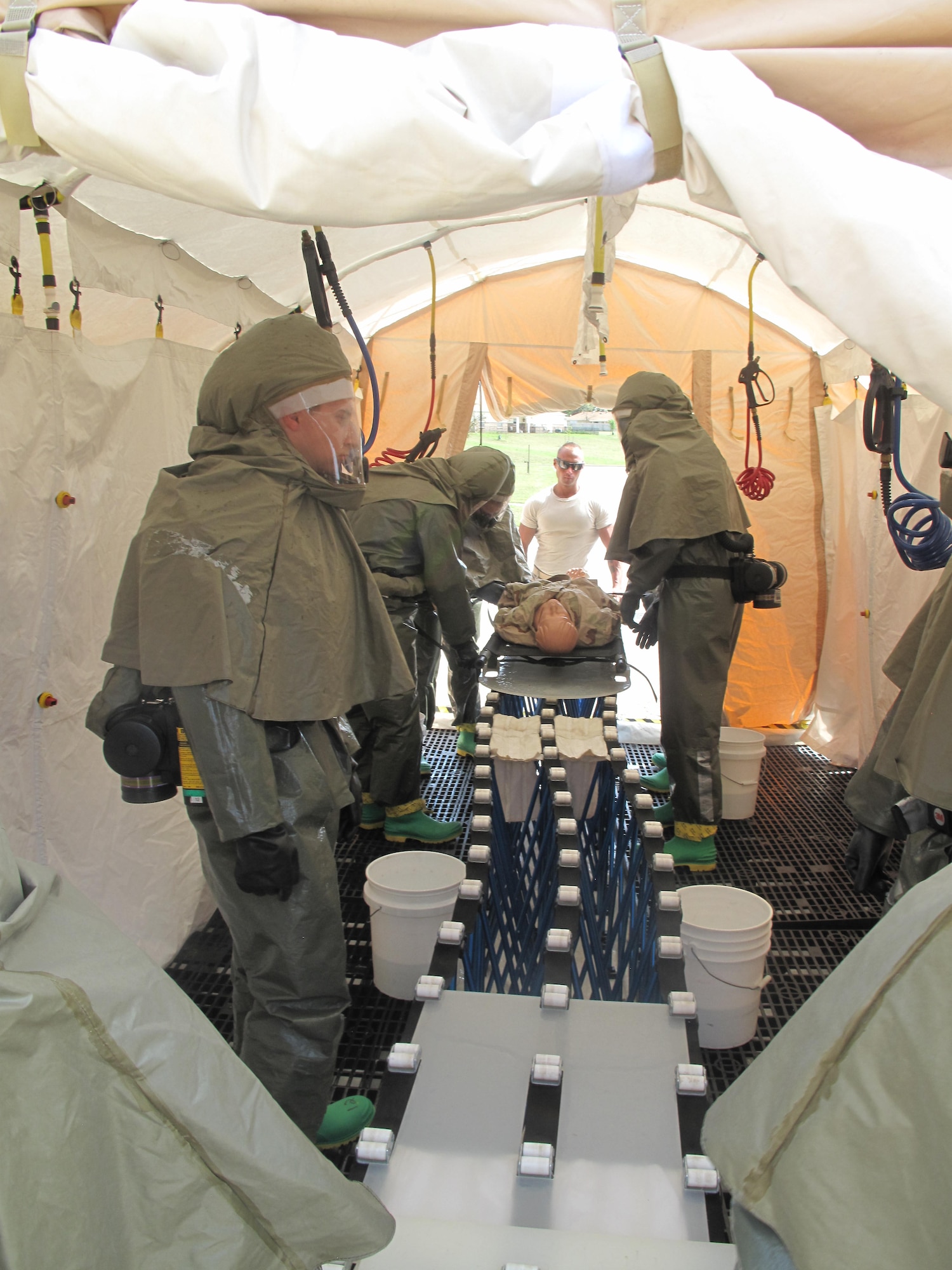 Members of the 17th Medical Group in-place patient decontamination disaster response team begin the decontamination procedures on a simulated patient outside of the 17th MDG Clinic on Goodfellow Air Force Base, Texas, April 2, 2015. The training helps the IPPD team to be ready for any type of chemical, biological, radiological or nuclear incident. (Courtesy photo)