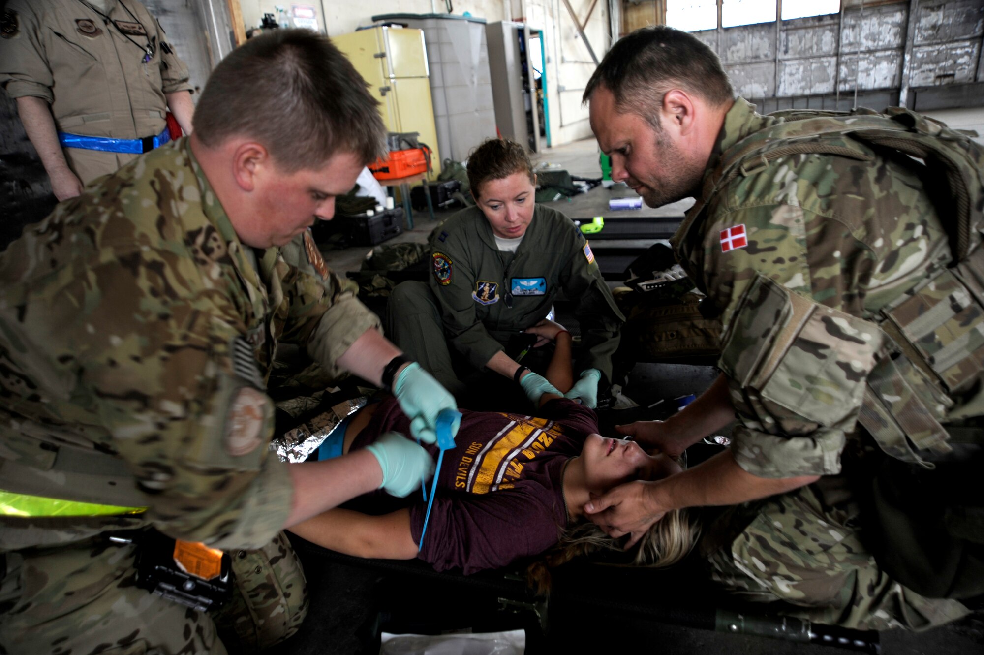 U.S. Air Force Airmen and a Royal Danish air force rescue member work together to treat a simulated flood victim with internal bleeding during an Angel Thunder 2015 mass casualty exercise at Winslow-Lindbergh Regional Airport, Ariz., June 5, 2015. Service members, University of Arizona and Northern Arizona University students acted as simulated patients to create a realistic experience during the exercise. (U.S. Air Force photo/Tech. Sgt. Courtney Richardson) 